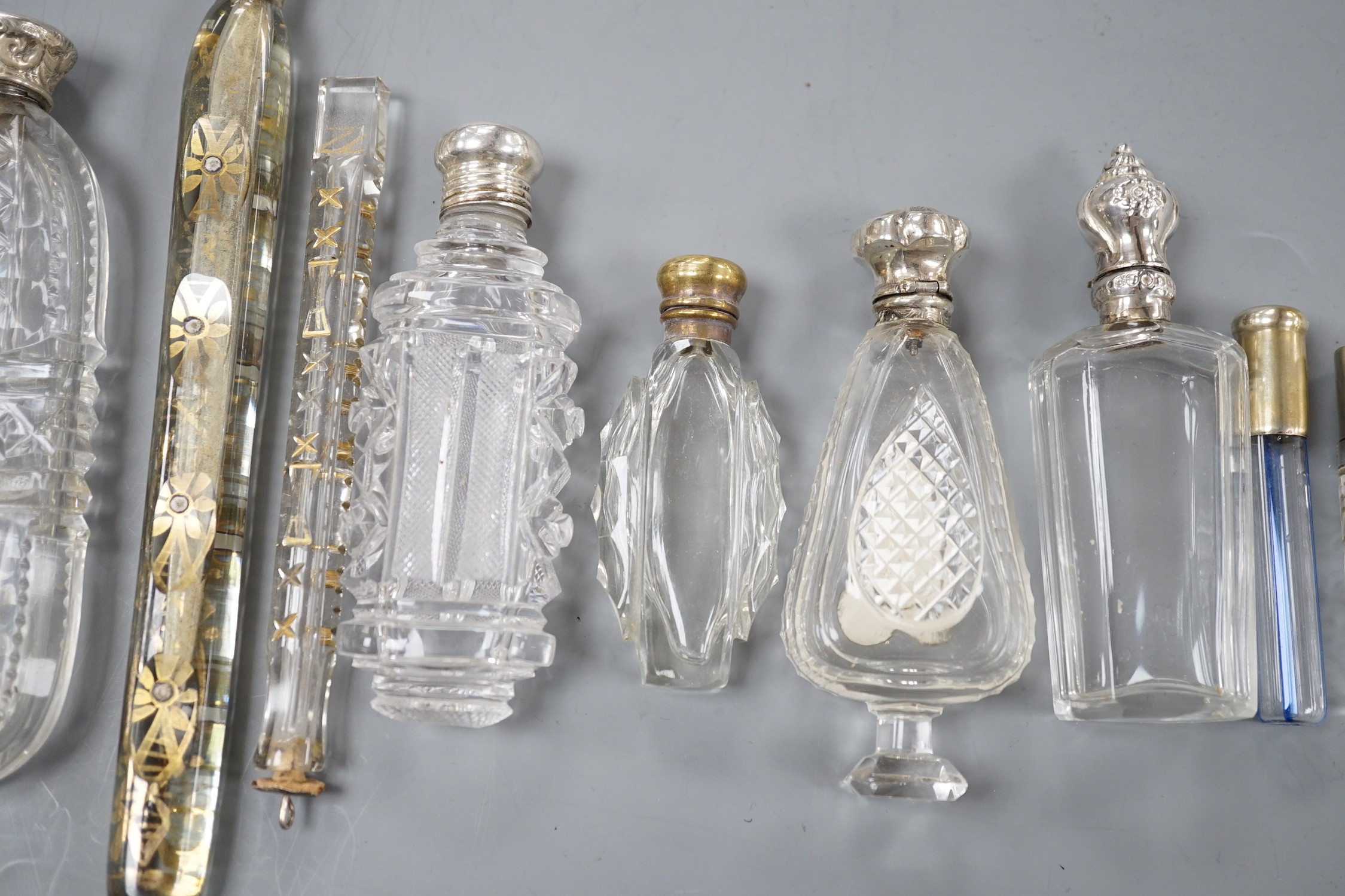 Nine assorted late 19th/early 20th century white or gilt white metal mounted glass scent bottles, including Austro-Hungarian gilt white metal and enamel mounted cylindrical scent by George Adam Scheid, largest 17.2cm.